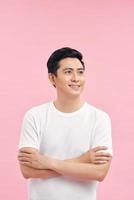 Smiling Asian man in t-shirt standing near blank wall. photo