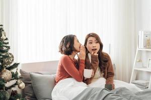 Happy female friends holding coffee mugs while discussing at table in living room relax time photo