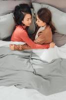 Two pretty best friends forever girlfriend talk, hug and laugh together on bed at cozy home relation fall in love photo