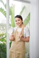 Cooking utensils. Cooking woman in kitchen with frying pan and wooden spoon. Housewife dancing. photo