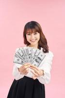 Portrait of a joyful woman showing dollars and showing gestures on a pink background. photo