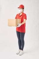 Delivery woman holding cardboard boxes in medical rubber gloves and mask on white background. photo