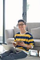 Freelancer Workday. Smiling millennial man employee student working studying from home sitting on floor carpet in living room. photo