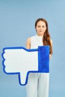 Attractive unhappy young woman holding social media symbol of dislike feeling sad and rejected in internet obsession photo