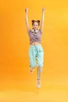 Full length photo of joyful lady jumping high listening modern youngster playlist music through cool earflaps isolated on yellow background