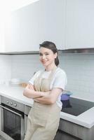 Portrait of young woman standing with arms crossed against kitchen background photo