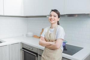 smiling, beautiful woman standing with crossed arms and looking at camera in kitchen photo