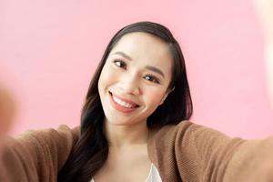 Image of excited happy young woman isolated over pink background make selfie by camera. photo