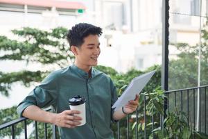 Man Reading Documents while standing on balcony garden photo