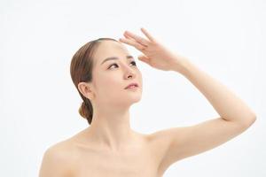 Portrait of young Asian woman looking to the side and showing hand on white background. photo