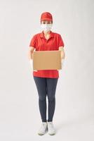 Delivery woman holding cardboard boxes in medical rubber gloves and mask on white background. photo