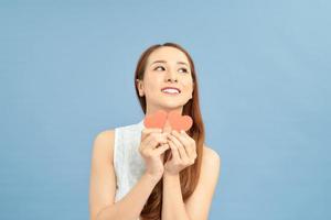 Portrait of thoughtful ponder girl in good mood having two little small red paper carton hearts in hands photo