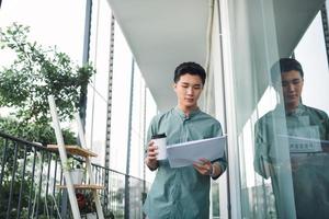 Man Reading Documents while standing on balcony garden photo