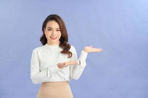 Full length portrait of a happy thoughtful woman holding copyspace on the palm isolated on a purple background photo