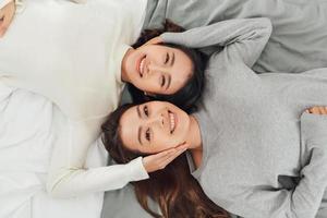 Two smiling women lie on bed photo