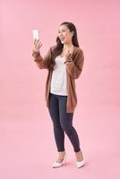 Young beautiful woman using mobile phone studio on pink color background photo