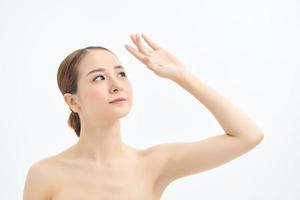 Close up of young naked Asian woman looking up and showing hand. Isolated on white background. photo