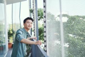 Handsome man leaning on rail and enjoying drink, isolated on city background with trees and buildings photo