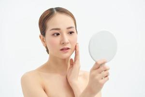 Beautiful Asian woman checking her skin, skin care, acne treatment. Spa and skincare concept. photo