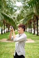 joven turista asiático sonriendo feliz usando una cámara vintage en la ciudad. foto