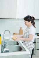 Happy Young Woman Washing Dishes in the kitchen photo