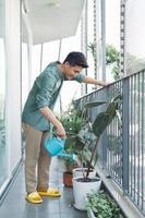 Man watering plant in container on balcony garden photo