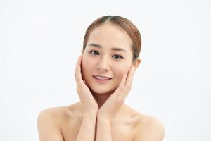 Beautiful young Asian woman with fresh clean skin that touches her face with both hands. Spa, cosmetology and beauty. photo