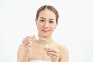 Portrait of young beautiful woman with skin care, serum product on white background photo