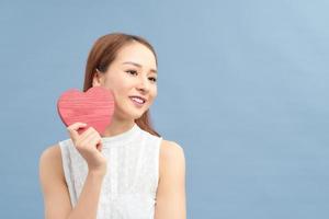 Love and valentines day woman holding heart smiling cute and adorable isolated on blue background. photo