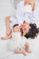 Smiley mother and her baby looking at you lying on the floor at home photo