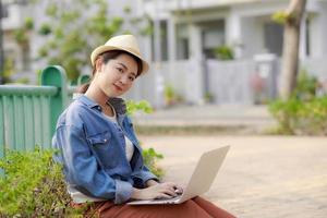 Young woman with laptop sits on couch in the park on a sunny day. photo
