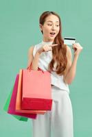 Young woman isolated on blue background holding shopping bags and surprised photo