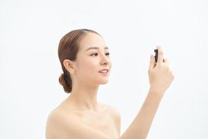 Beautiful asian woman applying spray water on face isolated white background. photo