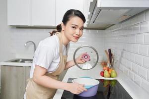 mujer joven de pie junto a la estufa en la cocina. foto