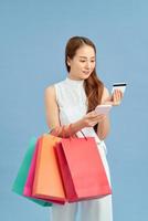 Stylish woman with shopping bag, credit card and phone on the blue wall background photo