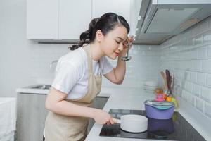 Young Woman Tasting Food With Spoon In Kitchen photo