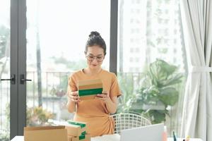 las mujeres asiáticas que venden productos en línea llevan una caja de paquetes con las manos para prepararse para la entrega a los clientes con pedidos foto