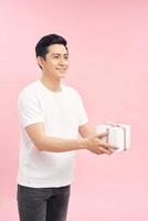 happy handsome man giving a christmas gift, on pink background photo