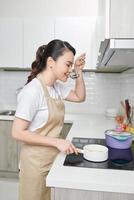 beautiful housewife cooking with ladle  in kitchen photo