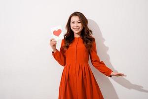 Attractive young woman reading a valentine card while standing isolated on white background photo