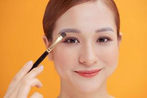 Portrait of a beautiful woman applying eye shadow photo