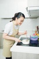 mujer joven cocinando en la cocina. comida sana. concepto de dieta. estilo de vida saludable. cocinar en casa. prepara comida foto