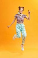 Atractiva chica alegre descuidada saltando escuchando bajo divirtiéndose aislado sobre fondo de color amarillo brillante foto