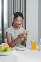 mujer joven usando su teléfono móvil mientras desayuna foto