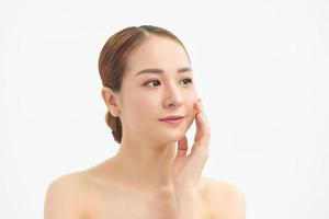 Portrait of young beautiful Asian woman touching her face with naked body over white background. photo