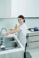 mujer joven lavó los platos en una cocina foto