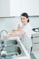 una joven atractiva está lavando platos mientras limpia en casa foto