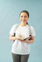 Portrait of a happy friendly girl student with backpack holding books  isolated over blue background photo