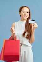 Shopping Woman concept, portrait or isolated an beautiful Asian woman wearing dress, holding shopping bags and credit cards. photo