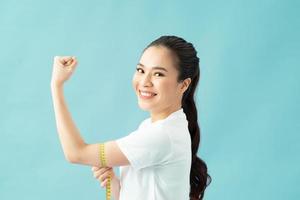 Woman measuring her excess arm fat by yellow measure tape on isolated background. photo